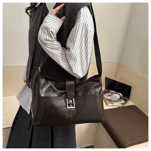 Detail view of a vintage dark brown shoulder bag with a silver buckle on a wooden desk