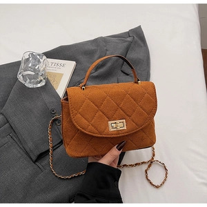 Detailed macro view of quilted brown suede bucket bag with gold clasp and chain strap