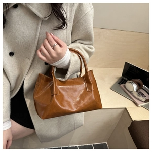 Close-up of brown oiled leather tote bag with soft vintage texture and double handles