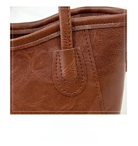 Detailed view of U-shaped double stitching and vintage leather texture on brown bucket bag