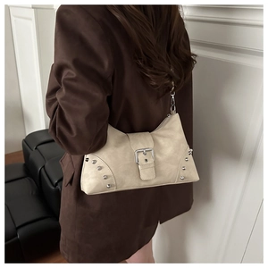 Detail of beige shoulder bag with silver rivets and buckle shown on a brown suede blazer