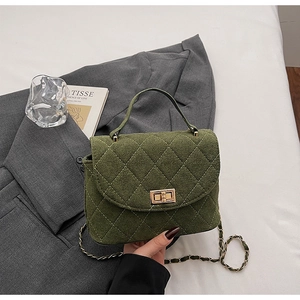 Detail of dark green quilted velvet bag with gold square lock and leather chain strap