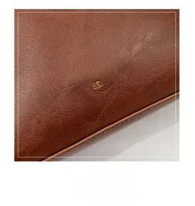 Close-up of brown litchi pattern leather bucket bag with gold embossed logo and stitching