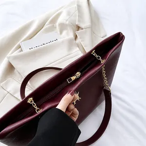 Détail du zip doré fluide et texture de cuir litchi sur sac cabas bordeaux chic