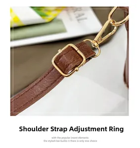 Detail of adjustable dark brown crocodile texture shoulder strap with gold metal buckles