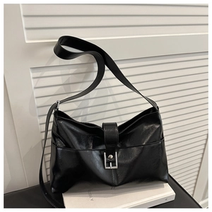 Detail of glossy black faux leather shoulder bag featuring a stylish silver metal buckle