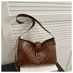 Detail view of a vintage brown leather bag with silver metal buckle on a white book