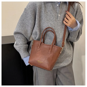 Close-up of a brown vintage bucket bag with elegant Fashion & Bag lettering on the textured leather