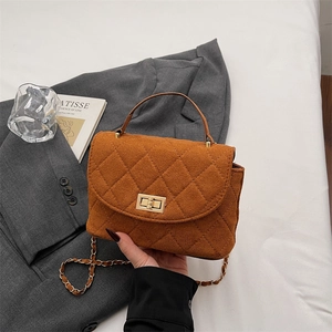 Caramel quilted suede handbag with gold chain strap and turn-lock closure on grey suit