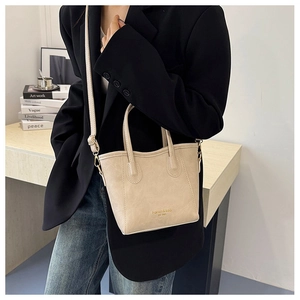 Close-up of beige leather bucket bag with top handle and adjustable gold hardware strap