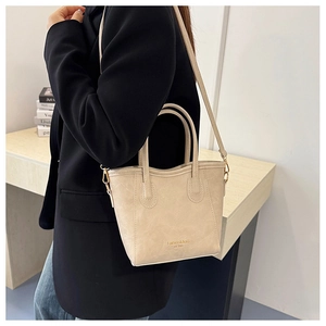 Close-up of cream faux leather tote bag with elegant texture and gold metal strap hooks