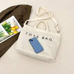 Sac fourre-tout en velours côtelé avec broderie et bandoulière montrée avec un smartphone