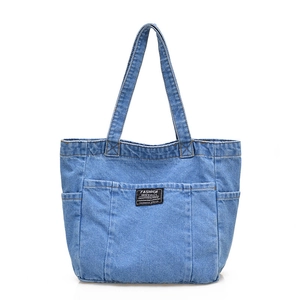 Blue denim tote bag with functional front pockets and a minimalist vintage design