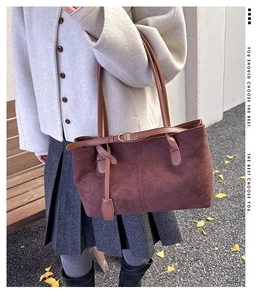 Détail du sac fourre-tout en daim marron foncé avec fines anses et boucle élégante