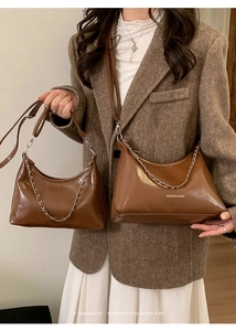 Detail of dark brown crescent hobo bag with silver chain strap and smooth PU leather