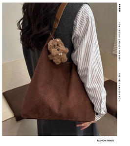Detail view of large brown frosted tote bag with a cute plush bear charm accessory