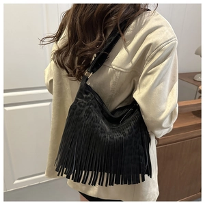 Detail der schwarzen Hobo-Tasche mit Leopardenmuster, langen Fransen und breitem Gurt