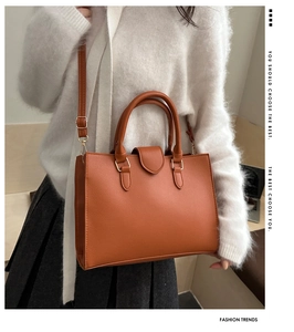 Detail of orange-brown pebble leather tote bag featuring golden hardware and straps