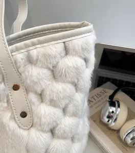 Detail of plush cream bucket bag featuring quilted faux fur and premium leather handles