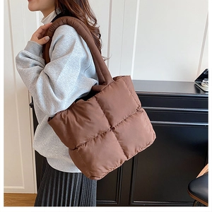 Detalle de bolso acolchado marrón con asas gruesas y textura suave para mujer
