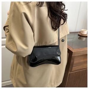 Detailansicht der schwarzen Lackleder-Schultertasche mit glänzendem Finish und gebogenem Boden