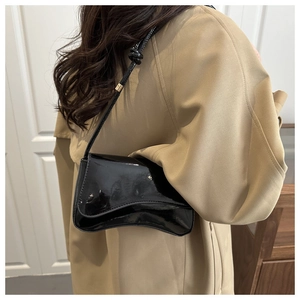 Detail einer minimalistischen, schwarzen Lackleder-Unterarmtasche mit glänzendem Finish