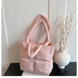 Bolso acolchado rosa con asas gruesas acolchadas en un ambiente doméstico minimalista