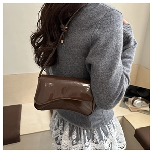 Detailed view of the coffee brown patent leather finish on a minimalist shoulder bag
