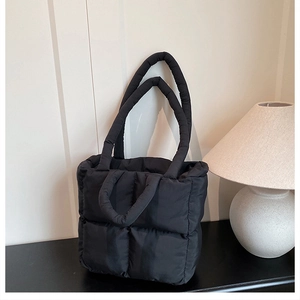 Vista detallada del bolso acolchado negro con costuras cuadradas y múltiples asas largas