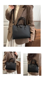 Close-up of black litchi pattern leather tote with golden buckles and round handles