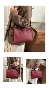Detailed view of burgundy tote bag showing pebbled leather texture and gold hardware