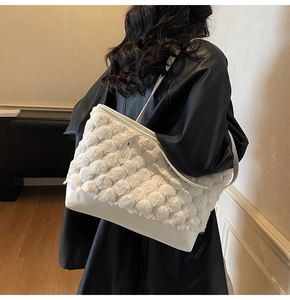 Detail of white plush textured bucket bag with leather base and gold hardware on model
