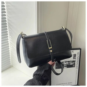 Close-up of black retro leather bag with golden buckle and textured finish details