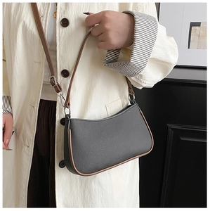 Detalle del bolso de media luna gris-negro con correas marrones en una modelo