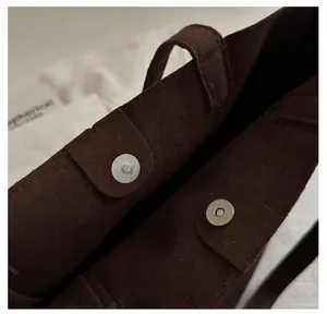 Détail du fermoir magnétique en métal sur le sac cabas vintage en daim marron