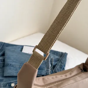 Dettaglio di una borsa a tracolla kaki con fibbia della tracolla e trama intrecciata