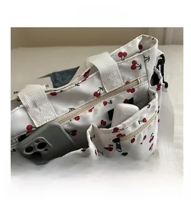 Detail of white canvas tote bag with cherry print showing front pockets and zipper storage