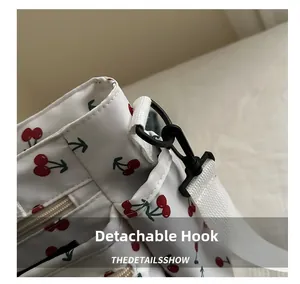 Detail showing the detachable black hook and white nylon shoulder strap on cherry tote bag