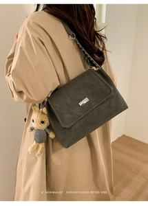 Détail du sac à bandoulière en daim gris foncé avec chaîne argentée et breloque lapin