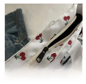 Detail shot of smooth black zipper closure on white cherry print tote bag fabric