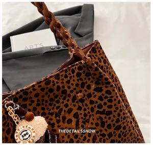 Détail du cabas léopard avec poignées tressées marron et breloque décorative en peluche