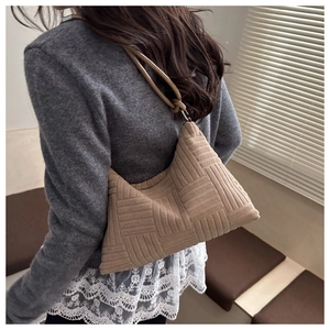 Detail of light brown woven tote bag with rectangular stitch texture and cylindrical handle