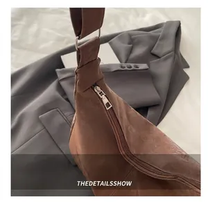 Détail de la fermeture éclair fluide et texture daim sur le sac bandoulière marron en métal