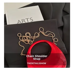 Close-up of red crescent bag with glossy mirror finish and fine gold chain strap
