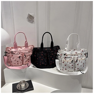Tre borse tote con stampa ciliegia in rosa, nero e bianco su un supporto da esposizione