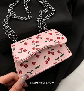 Detailed close-up of pink cherry print mini bag with golden metal chain strap texture