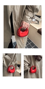 Close-up of a glossy red oval mini handbag with a delicate gold chain shoulder strap