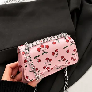Close-up of pink mini chain bag with cherry print and silver magnetic buckle detail