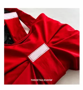 Detailopname van een rode nylon top met stijlvolle rimpelingen en decoratieve stiksels
