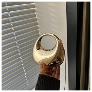 Detail of glossy gold water drop evening bag with circular handle and fine metal chain